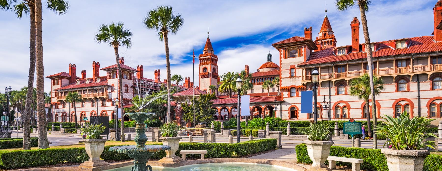 a fountain in a pool in front of a building with palm trees