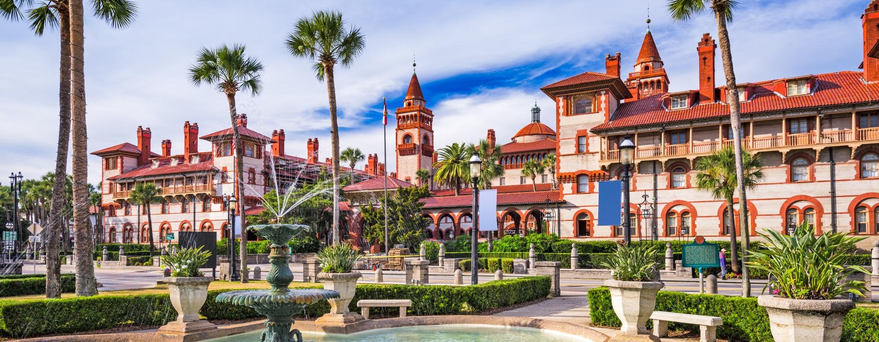 a fountain in a pool in front of a building with palm trees