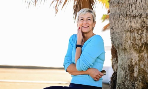 a person sitting near a tree at the beach